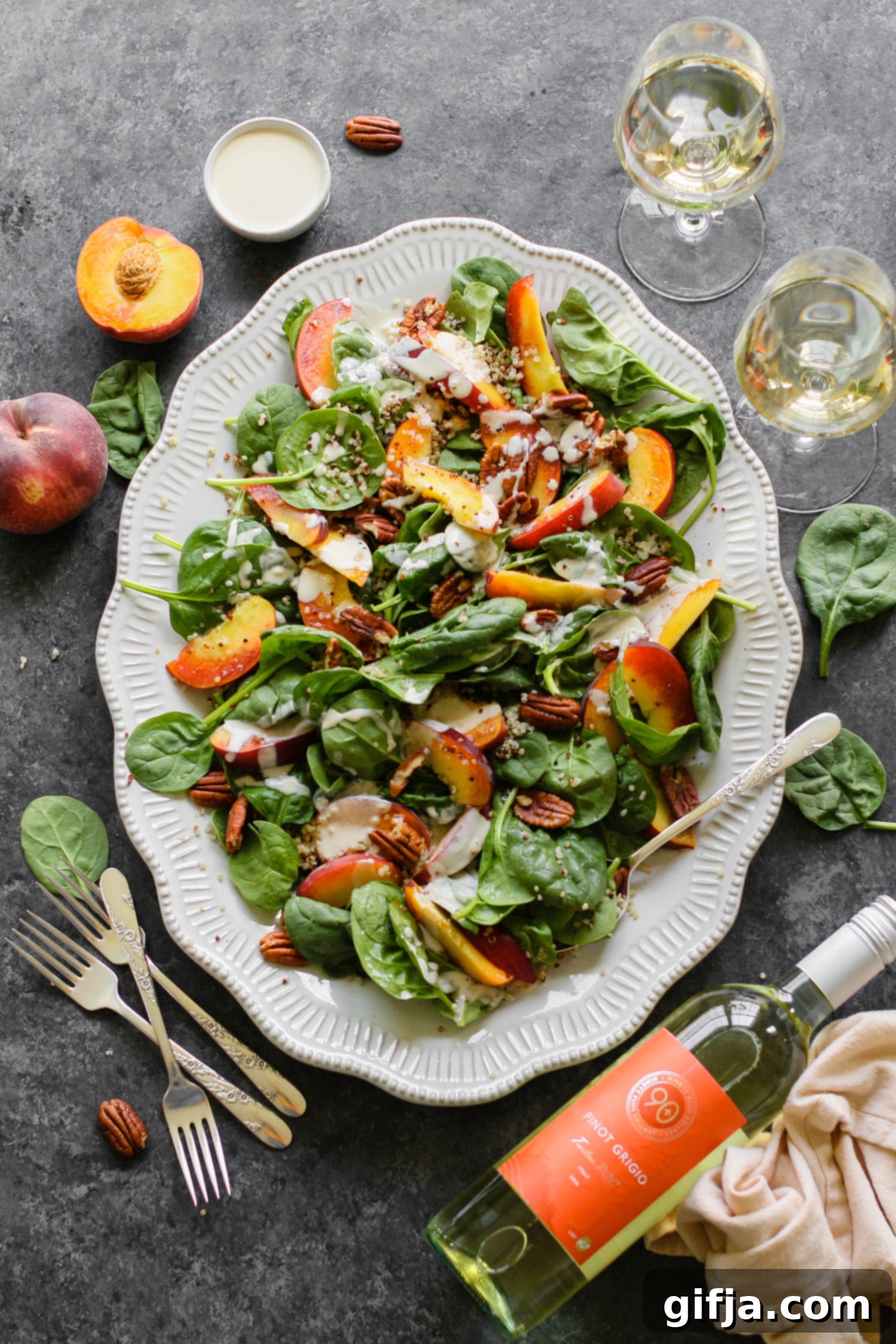 Peaches and Quinoa Salad with Pinot Grigio 25 A vibrant peach quinoa salad in a bowl, featuring sliced peaches, green spinach, and quinoa, ready to be served. Ideal for a light summer meal.