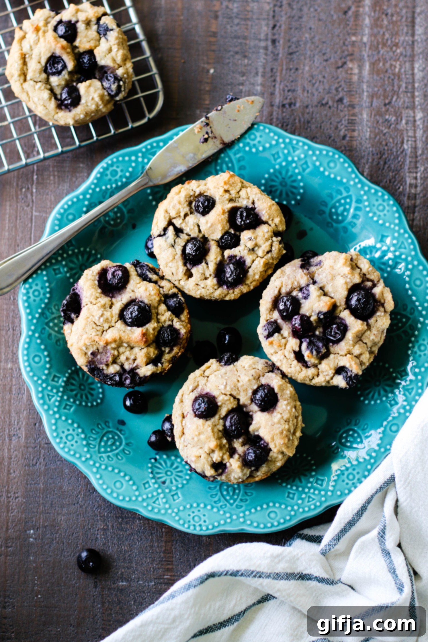 Ultimate Vegan and Gluten-Free Blueberry Muffins 2 The Best Vegan & Gluten Free Blueberry Muffins served on blue plate with a knife on wooden board