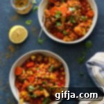 Vibrant One-Pot Chana Masala 7 A top-down view of a white bowl filled with 1-Pot Vegetable Chana Masala, garnished with fresh cilantro and a lemon wedge, sitting on a blue wooden surface.