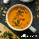 Roasted Pumpkin and Vegetable Soup 9 A top-down view of a creamy Roasted Pumpkin & Vegetable Soup garnished with fresh herbs and pumpkin seeds.