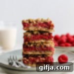 Jammy Raspberry Oat Crumble Bars 10 A top-down view of a single Raspberry Oat Crumble Bar on a white surface, showcasing its layers.