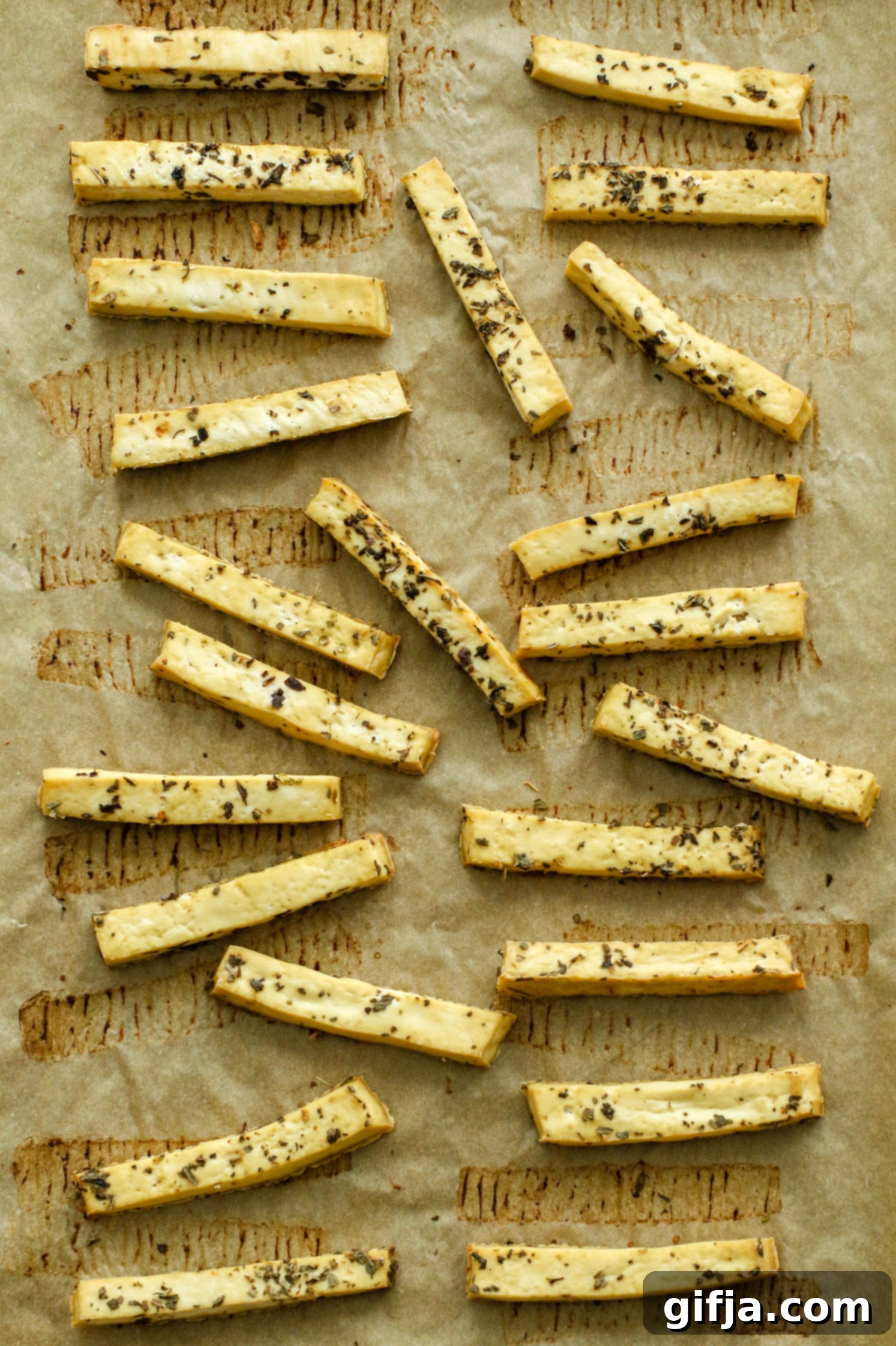 Crispy golden brown oven baked tofu fries arranged on a baking sheet, ready to be served as a healthy snack or side dish.