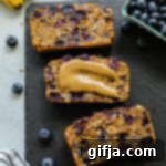 Sweet Morning Berry Banana Loaf 11 A whole loaf of Blueberry Banana Breakfast Bread on a small plate, ready for serving.