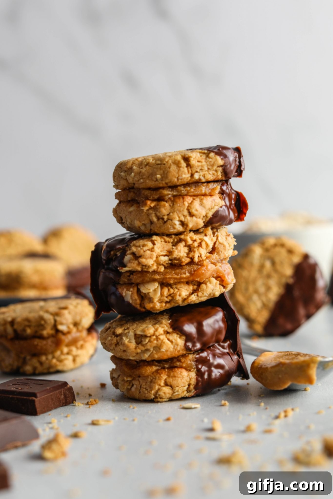 Chocolate Dipped Vegan Do-Si-Dos stacked on wooden board with spoon of peanut butter by Flora & Vino
