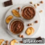 2-Ingredient Roasted Hazelnut Chocolate Delight 12 2-Ingredient Roasted Hazelnut Nutella in a small jar, next to raw hazelnuts and chocolate chunks