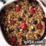 Berry Bliss Baked Oatmeal 11 Berry Baked Oatmeal in baking dish with spoon and granola and berries on the side