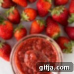 Simple Strawberry Chia Seed Jam 6 Strawberry Chia Seed Jam served in mason jar with a spoon surrounded by fresh strawberries