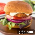 Wholesome Sweet Potato Black Bean Burgers 12 Close up shot of a Sweet Potato Black Bean Burger in a bun, garnished with lettuce and tomato.