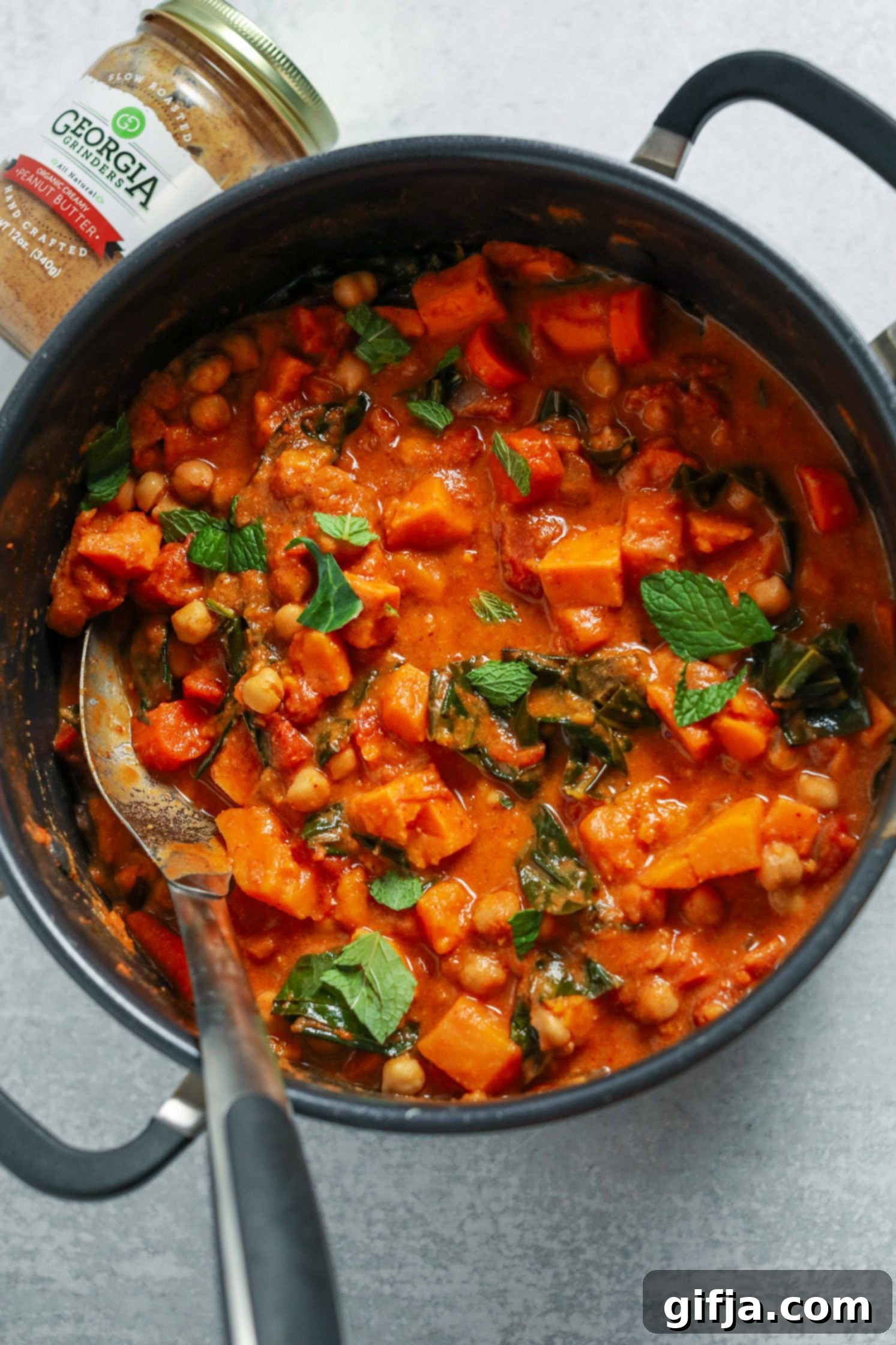 Golden Groundnut Pot 4 African Peanut Butter Stew cooked in pot with a big spoon by Flora & Vino