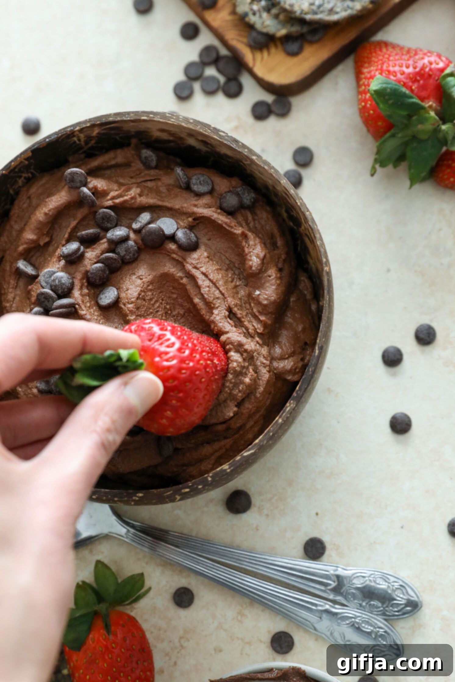 hand dipping strawberry into Vegan Brownie Batter Dip by Flora & Vino