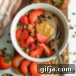 Cocoa Protein Dream Bowl 15 A vibrant Chocolate Protein Yogurt Bowl served in a stylish bowl on a rustic wooden board, generously topped with diced strawberries, creamy SunButter drizzle, dark chocolate chips, and crispy granola