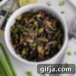 The Illicit Stir-Fry 15 Forbidden Fried Rice with asparagus, shiitake mushrooms, and steamed edamame, served in a white bowl with green onions and sesame seeds, alongside lime and sriracha aioli.