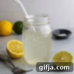 Homemade Hydration Elixir 10 Homemade Electrolyte Water served in mason jar with glass straw and lemons and limes scattered