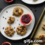 Vibrant Blood Orange Chocolate Chickpea Cookies 10 A single Blood Orange Chocolate Chip Chickpea Cookie on a white plate with blood orange slices.