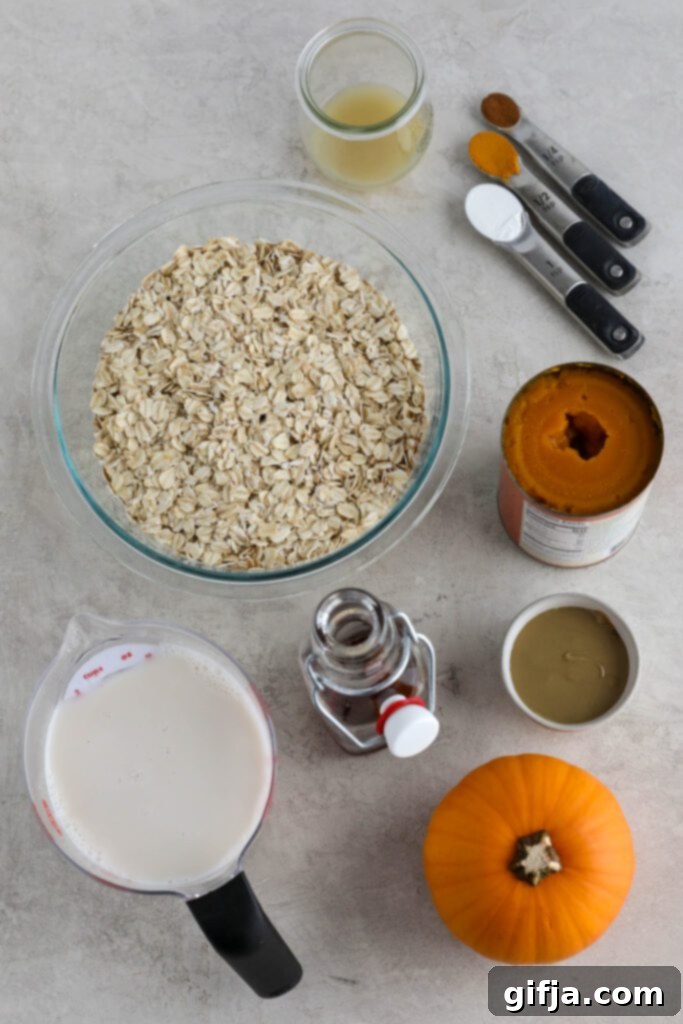 Assortment of fresh ingredients for pumpkin turmeric waffles, including pumpkin puree, oats, spices, and Navitas Organics turmeric and cacao products laid out on a wooden surface