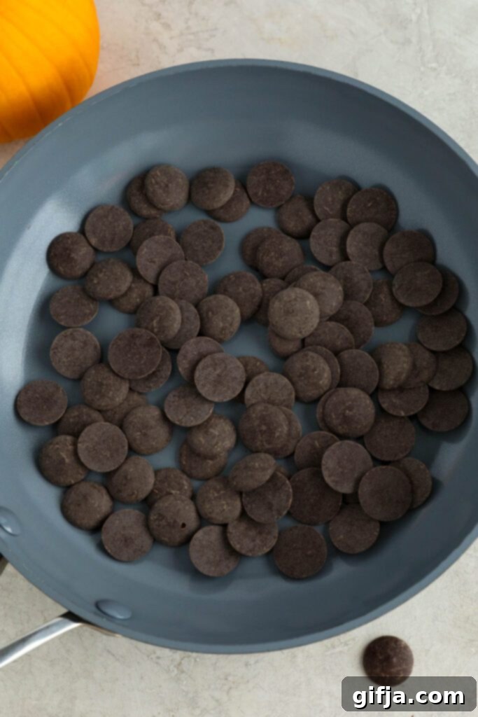 Navitas Organics cacao wafers arranged in a pan alongside a fresh pumpkin, illustrating the quality ingredients used for the delicious chocolate drizzle for the waffles