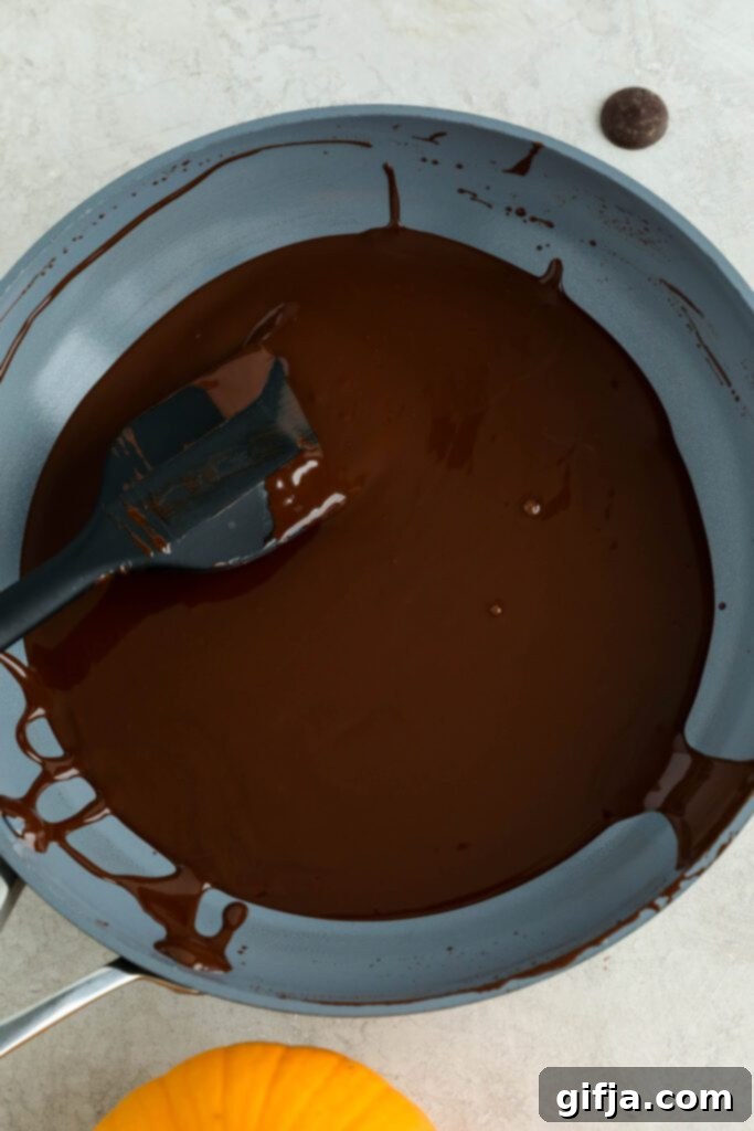 Melted Navitas Organics cacao wafers stirred in a pan with a spatula, creating a rich chocolate drizzle for the pumpkin turmeric waffles