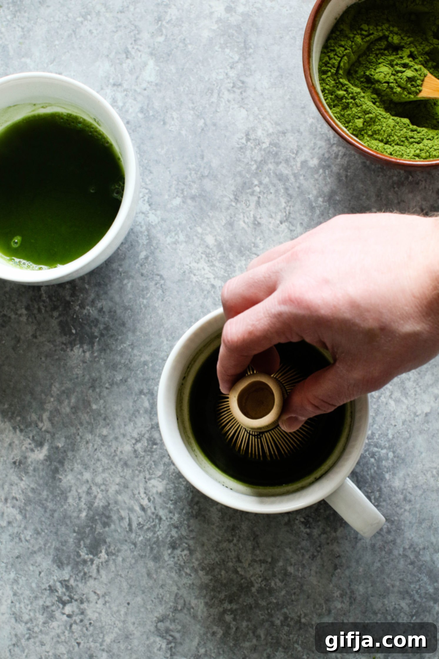Hand whisking matcha in mugs by Flora & Vino