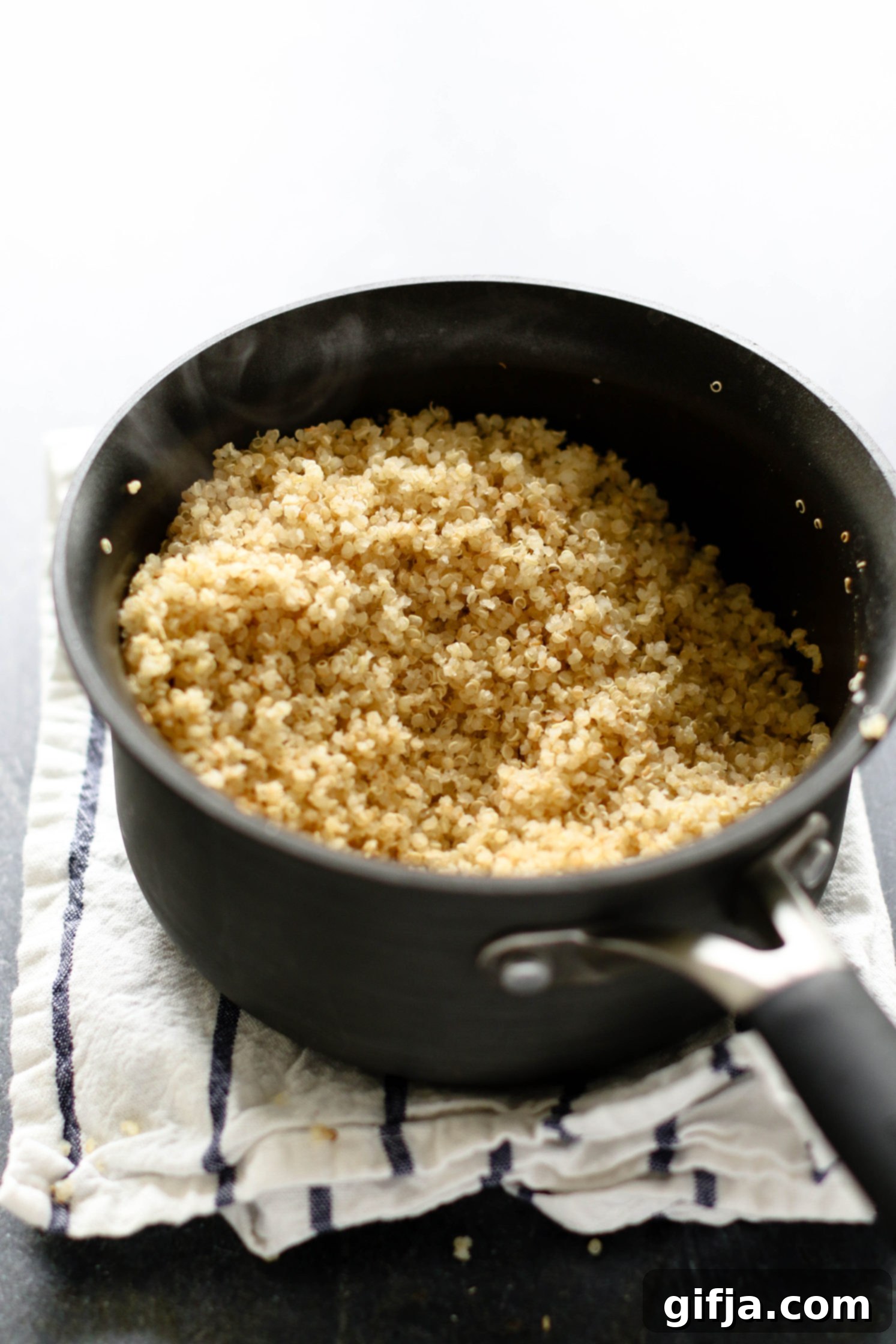 Vibrant Roasted Carrots 5 toasted quinoa in large sauce pot on top of white and blue striped towel