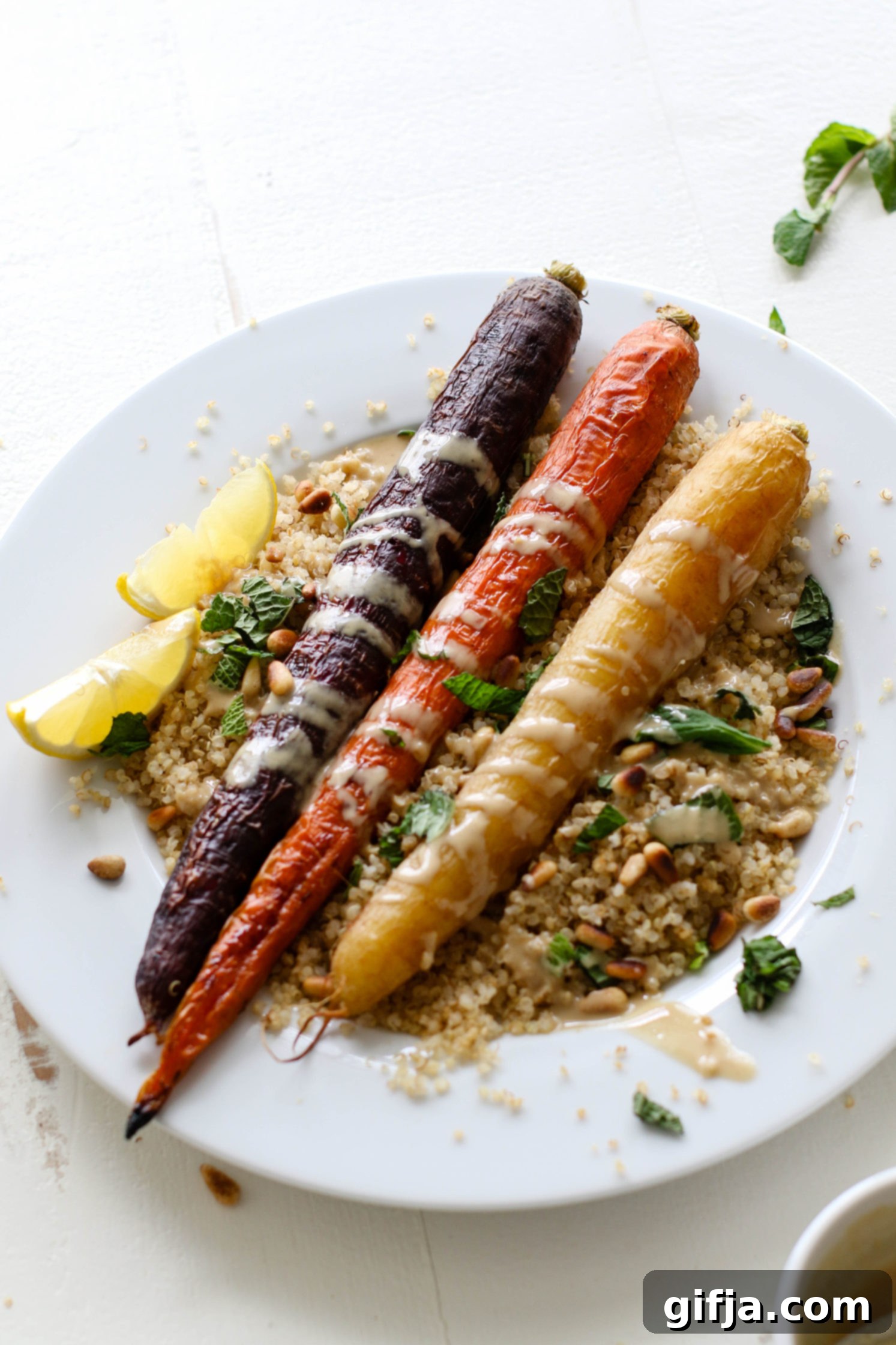 Vibrant Roasted Carrots 6 Rainbow Roasted Carrots served on plate over quinoa with fresh lemon, shredded mint, toasted pine nuts, and drizzle of tahini