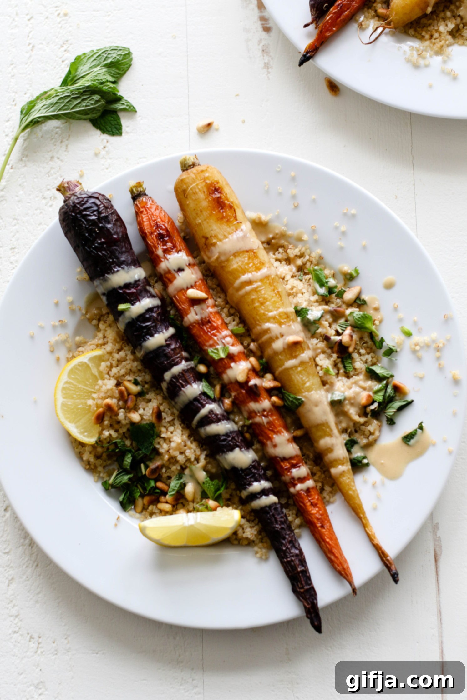 Vibrant Roasted Carrots 7 Rainbow Roasted Carrots served on plates over quinoa with fresh lemon, shredded mint, toasted pine nuts, and drizzle of tahini