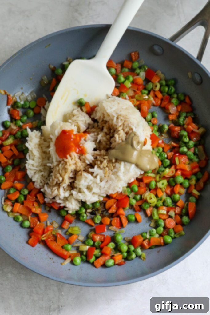 Solo Fried Rice Delight 6 rice, chili garlic sauce, and SunButter added to sautéed vegetables in pan with spatula