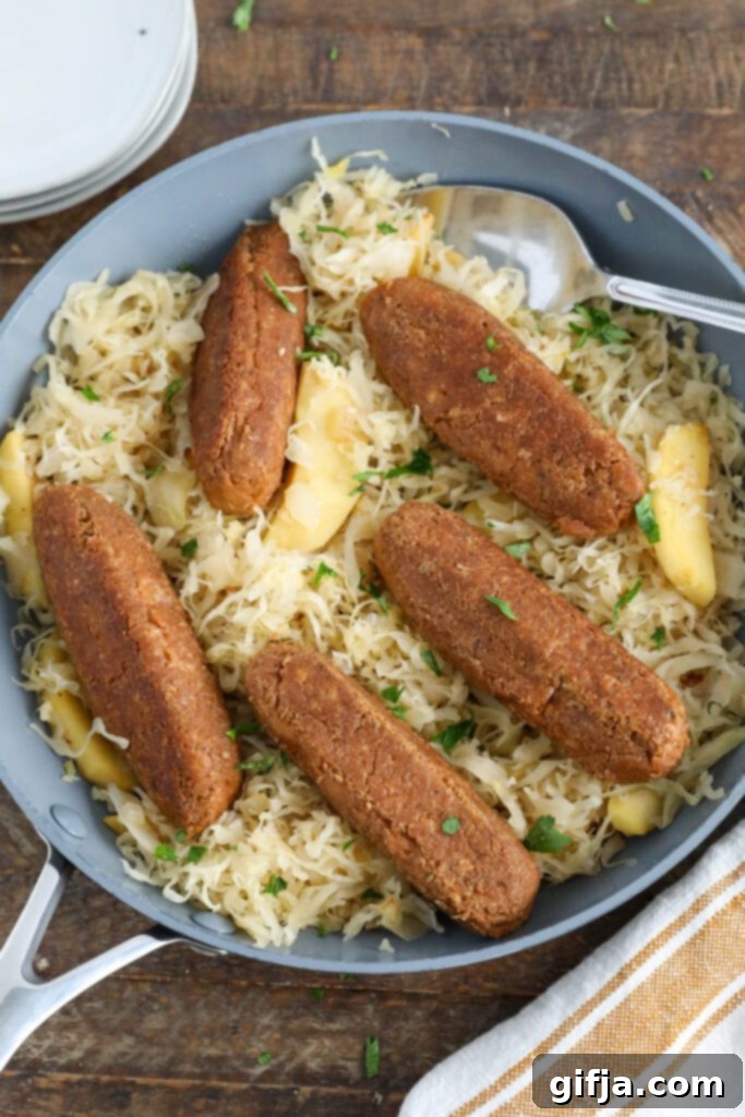 Vegan Bratwurst with Sauerkraut in pan with spoon topped with parsley
