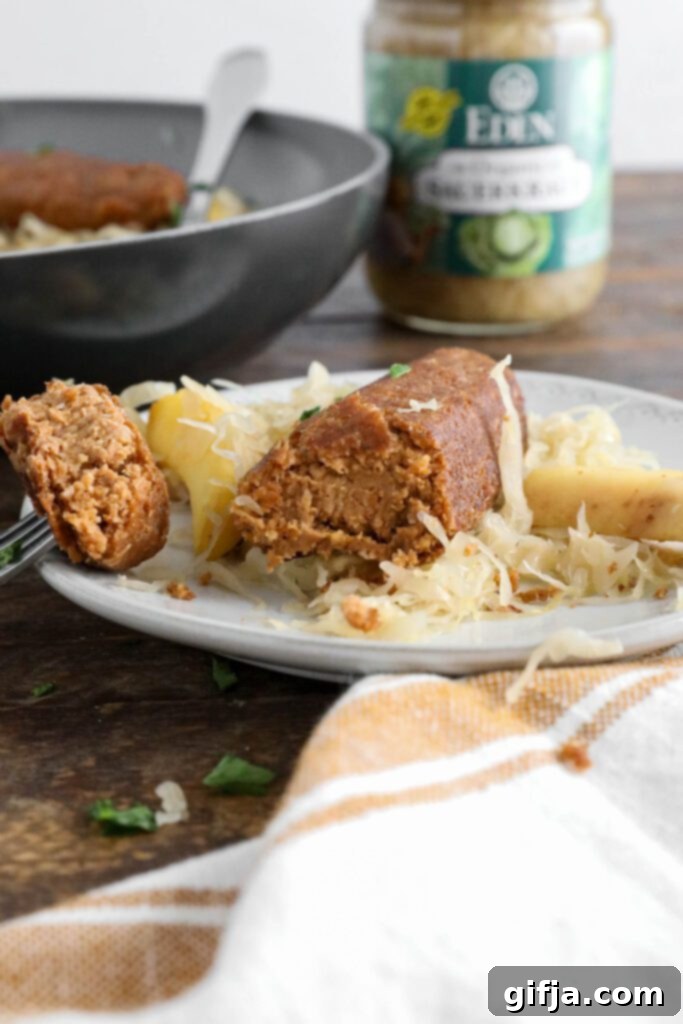 Vegan bratwurst on plate topped with sauerkraut