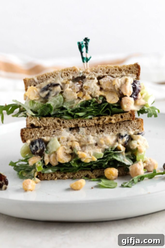 Stacked Cranberry Chickpea Salad Sandwich on a white plate with fresh greens