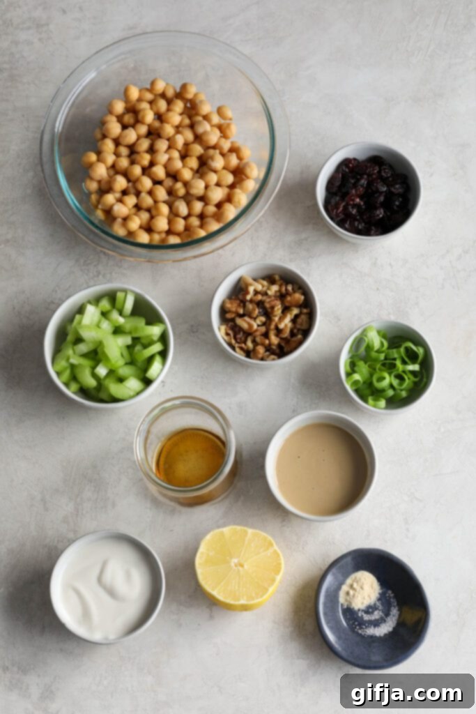 Bowls of fresh ingredients for chickpea salad including chickpeas, walnuts, cranberries, and celery