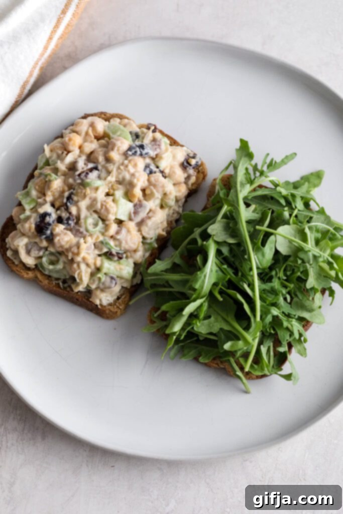 Cranberry Chickpea Salad Sandwich on toasted sourdough bread with fresh arugula, ready to be topped
