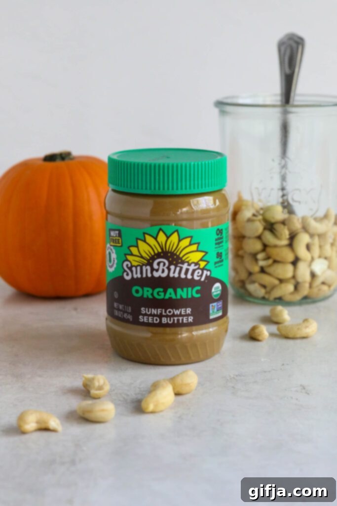 Spiced Pumpkin Cheesecake with Silky SunButter Frosting 3 SunButter jar on board with cashews and pumpkin behind it, ingredients for vegan pumpkin cheesecake