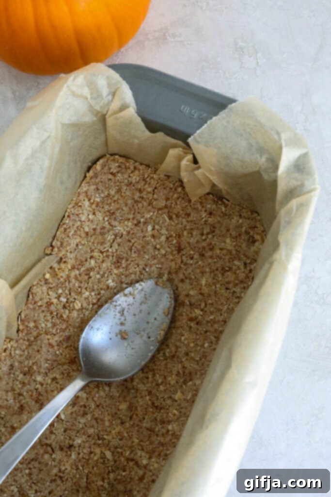 Spiced Pumpkin Cheesecake with Silky SunButter Frosting 4 crust for pumpkin pie cheesecake pressed into parchment lined bread pan, ready for baking