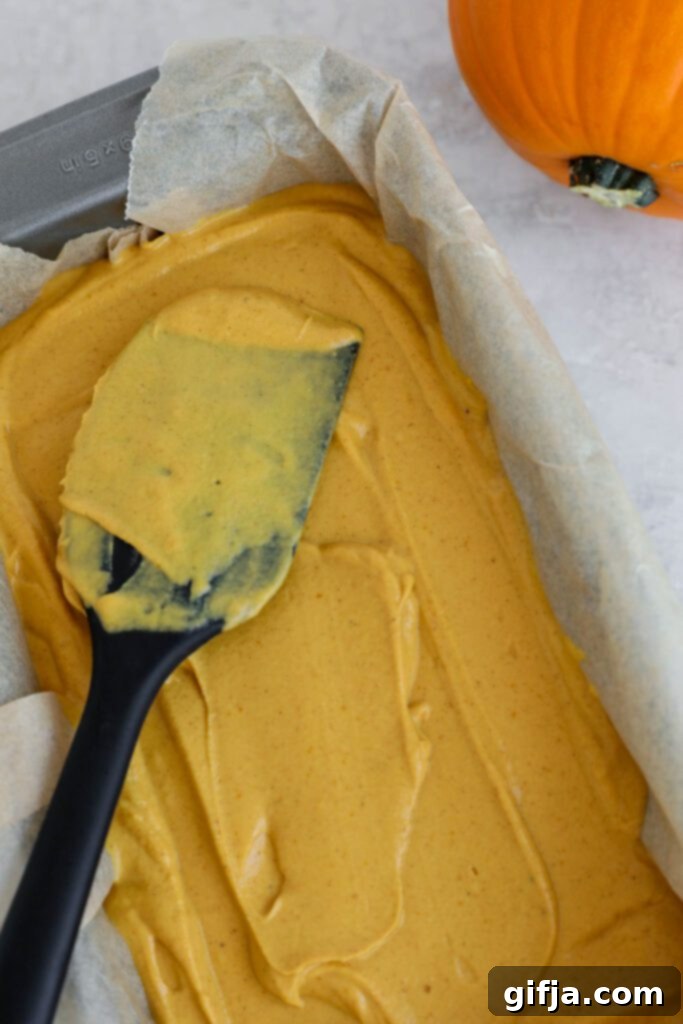 Spiced Pumpkin Cheesecake with Silky SunButter Frosting 7 pumpkin pie filling spread on top of crust in bread pan, ready for baking