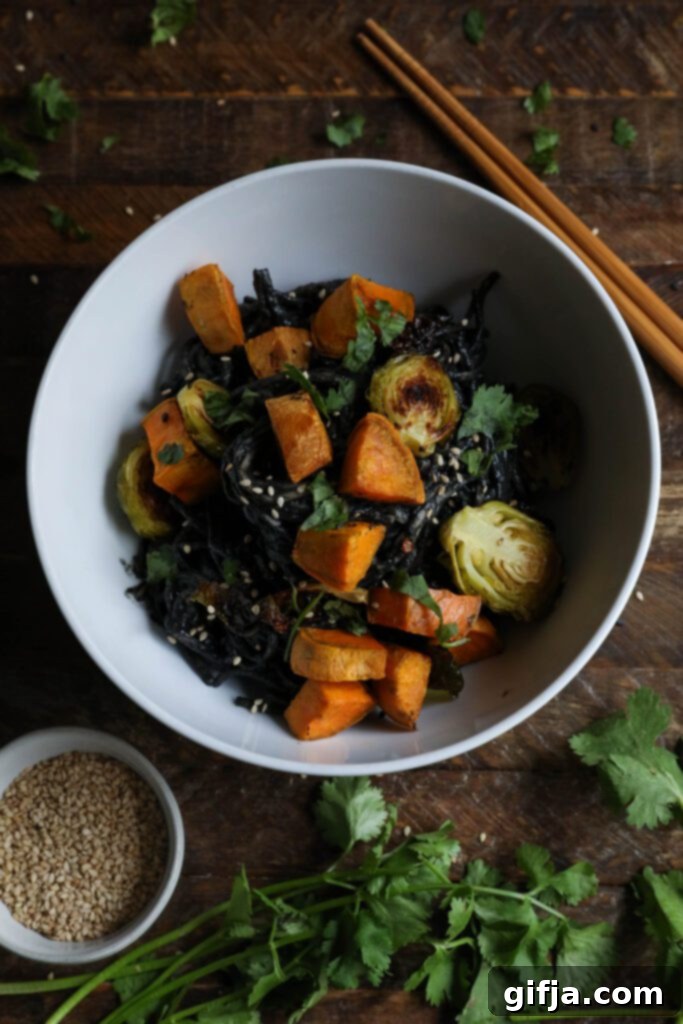 Black Sesame Noodle Bowl served in bowl topped with cilantro and sesame seeds, ready to be enjoyed.