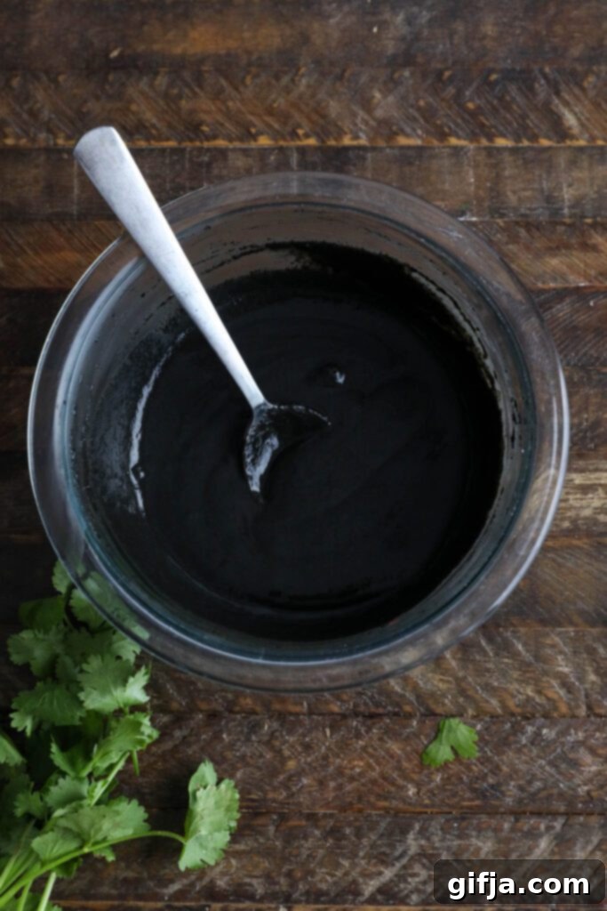 Midnight Sesame Noodle Bowl 5 Creamy Black Sesame Butter sauce mixed in a bowl with a spoon, highlighting its dark, luxurious texture.