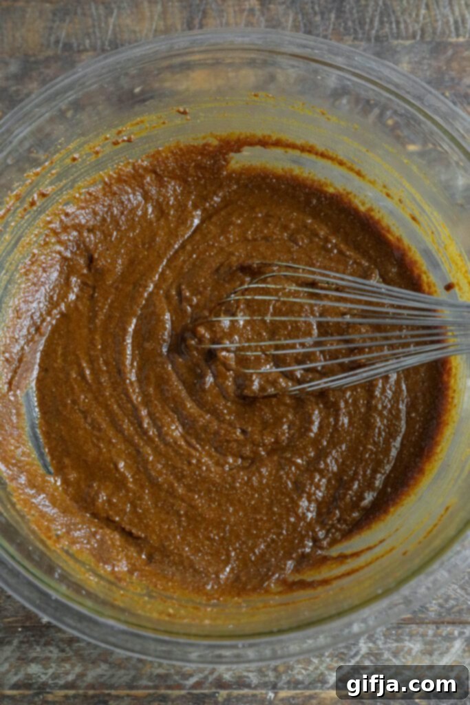 ingredients for gingerbread loaf mixed together in bowl with whisker